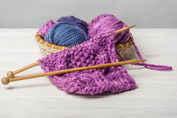 Close up view of knitting in wicker basket on white tabletop on grey backdrop — Stock Photo