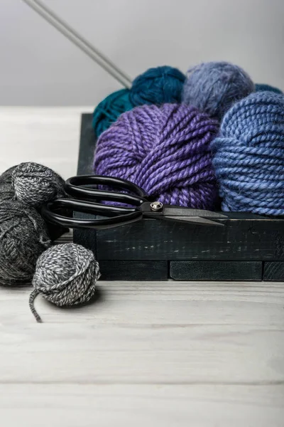 Close up view of yarn balls and scissors in wooden box on white tabletop — Stock Photo