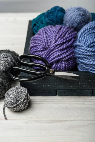 Close up view of yarn balls and scissors in wooden box on white tabletop — Stock Photo