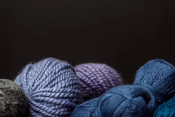 Close up view of purple, blue and grey yarn balls on black backdrop — Stock Photo