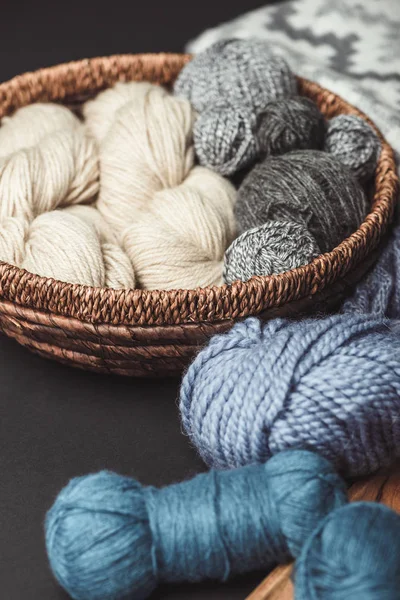 Close up view of knitting clews in wicker basket on dark tabletop — Stock Photo