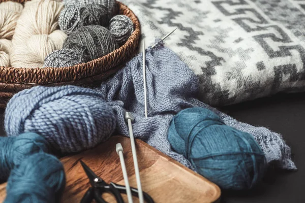 Close up view of knitting, scissors and knitting needles on dark tabletop with blanket — Stock Photo