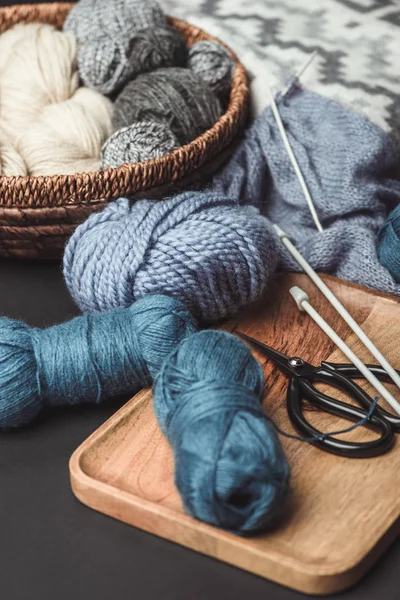 Close up view of knitting, scissors and knitting needles on dark tabletop with blanket — Stock Photo