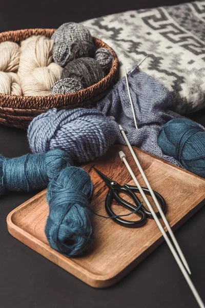 Close up view of knitting, scissors and knitting needles on dark tabletop with blanket — Stock Photo