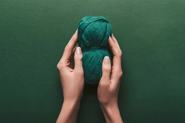 Tiro recortado de mujer sosteniendo hilo sobre fondo verde - foto de stock