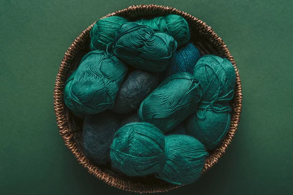 Верхний вид зеленой и синей пряжи прилипает в плетеной корзине на зеленом фоне — стоковое фото