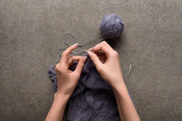 Partial view of woman knitting yarn on grey backdrop — Stock Photo