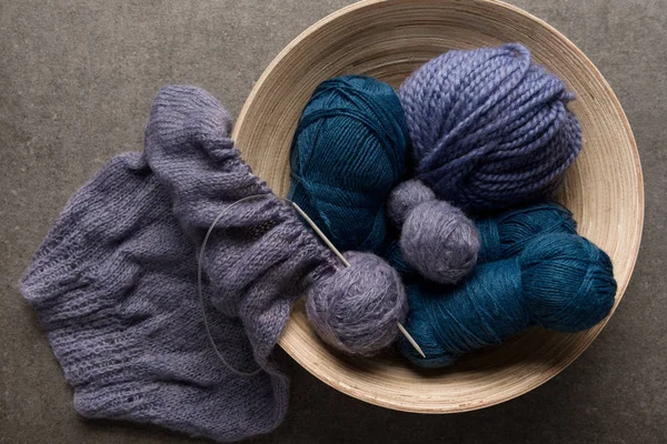 Flat lay with purple and blue yarn balls in bowl on grey background — Stock Photo