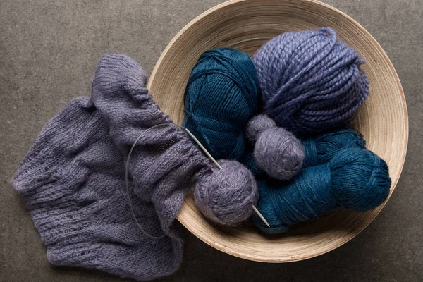 Couché plat avec des boules de fil violet et bleu dans un bol sur fond gris — Photo de stock