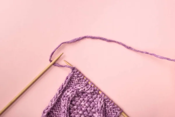 Deitado plano com fios roxos e agulhas de tricô na superfície rosa — Fotografia de Stock