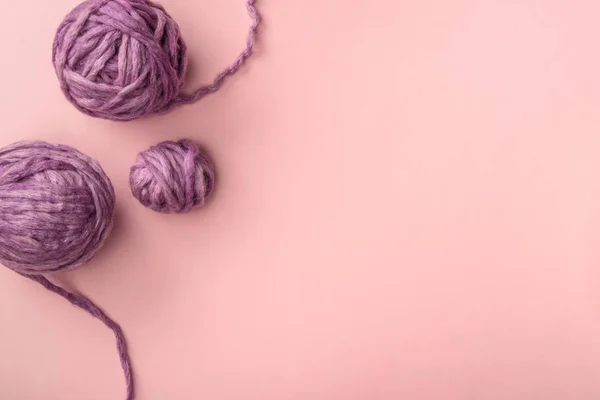 Вид сверху на фиолетовые вязальные шарики на розовом столе — стоковое фото