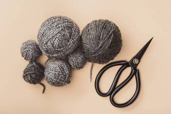 Flat lay with grey knitting and scissors on beige backdrop — Stock Photo