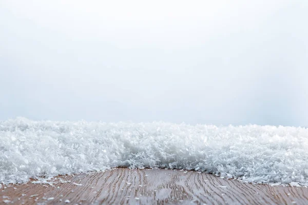 Tablero texturizado rayado marrón cubierto de nieve sobre blanco - foto de stock