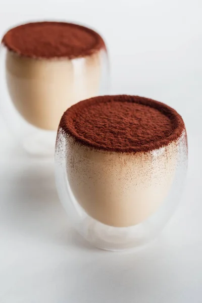 Sweet tiramisu desserts with cocoa powder in two glasses — Stock Photo
