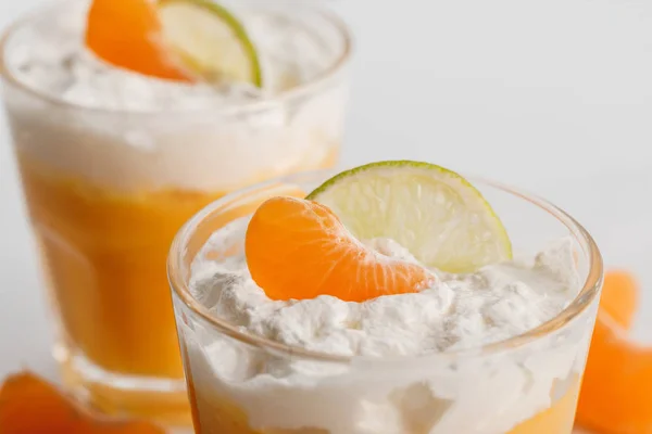 Perto de dois copos de sobremesas de creme com tangerina e fatias de limão — Fotografia de Stock