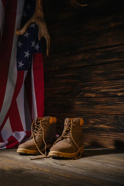 Trekking boots, horns and american flag on wooden surface, travel concept — Stock Photo