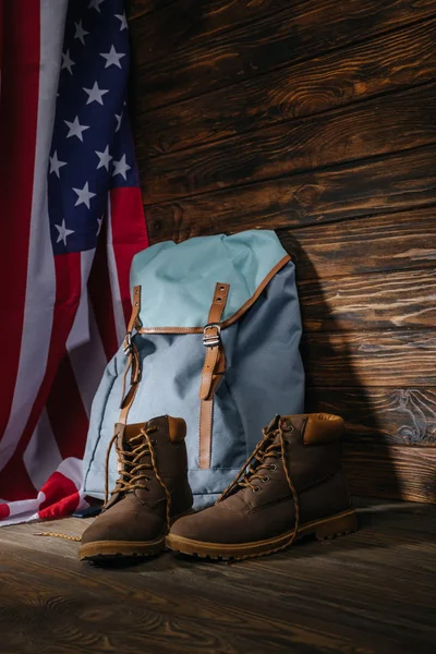 Botas de trekking, mochila e bandeira americana na superfície de madeira, conceito de viagem — Fotografia de Stock