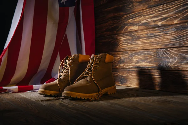 Trekking boots and american flag on wooden surface, travel concept — Stock Photo