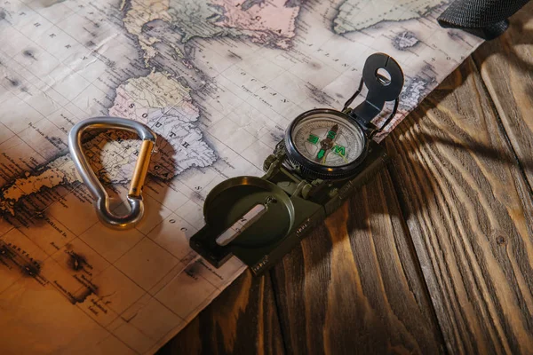 Крупный план компаса, пружинного крючка и карты на деревянном столе — стоковое фото