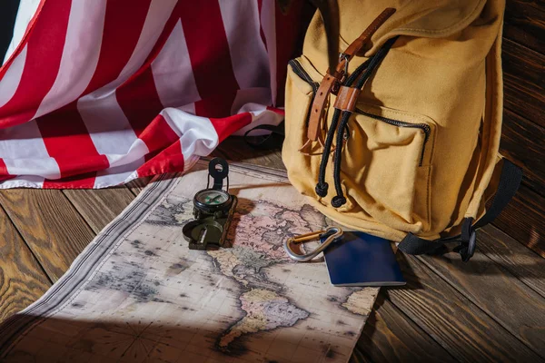 Backpack, compass, passport, map and american flag on wooden surface — Stock Photo