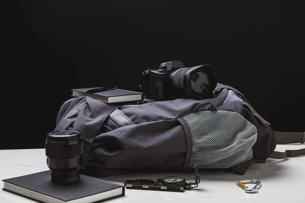 Rucksack, Fotokamera und Wanderausrüstung auf schwarz — Stockfoto