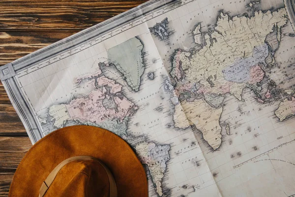 Top view of brown hat and map on wooden table, travel concept — Stock Photo