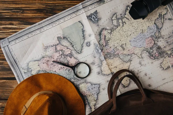 Top view of brown leather bag, hat, magnifying glass and photo camera on map — Stock Photo
