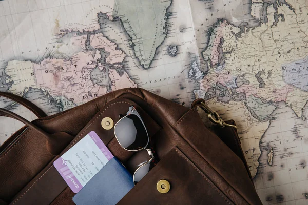 Vista superior de la bolsa de cuero con pasaporte, billete, gafas de sol y mapa. concepto de viaje - foto de stock