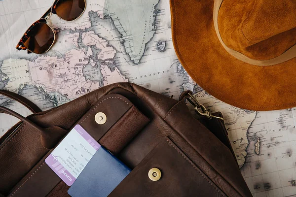 Vista superior do saco de couro, passaporte, bilhete, óculos de sol, chapéu e mapa — Fotografia de Stock
