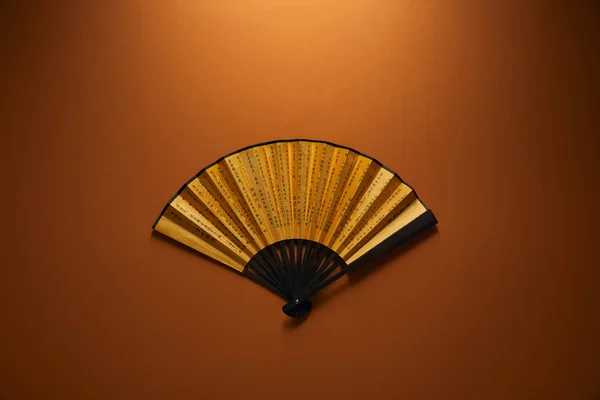 Top view of decorative black and golden fan with hieroglyphs on brown background, chinese new year concept — Stock Photo