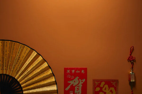 Top view of fan with hieroglyphs on brown background, chinese new year composition — Stock Photo