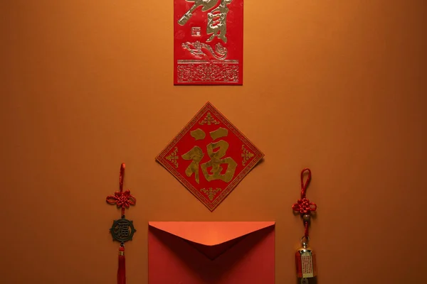 Enveloppe rouge, hiéroglyphes et décorations traditionnelles sur fond brun, concept Nouvel An chinois — Photo de stock