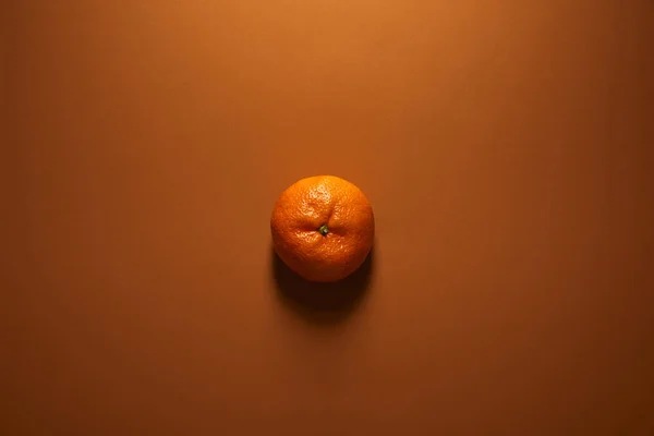 Top view of whole single ripe tangerine on brown background — Stock Photo