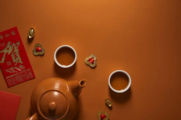 Vista superior del juego de té y decoraciones chinas tradicionales sobre fondo marrón - foto de stock