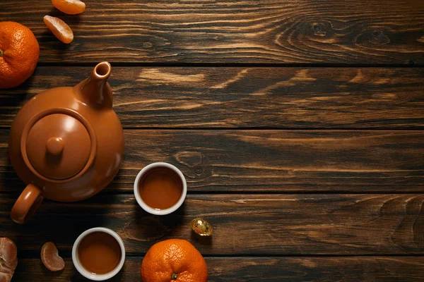 Верхний вид коричневый керамический чайник и мандарины на деревянный стол, китайский новый год концепции — стоковое фото