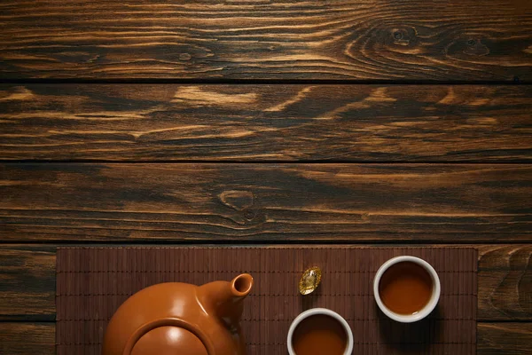 Top view of brown ceramic teapot and cups of tea on bamboo mat, chinese new year concept — Stock Photo