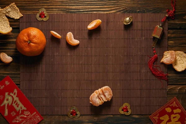 Top view of tangerines and traditional chinese decorations on bamboo mat, chinese new year concept — Stock Photo