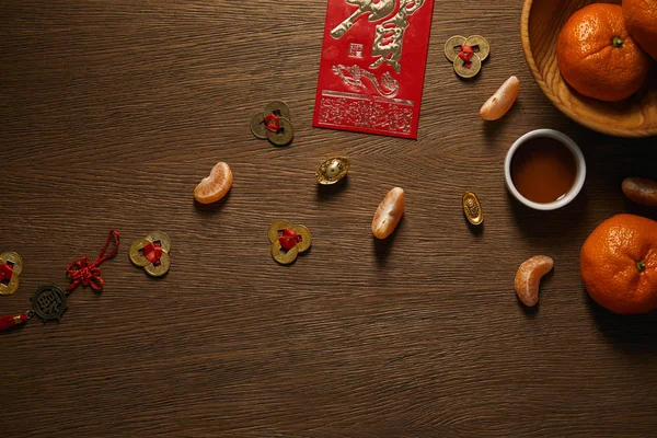 Top view of fresh ripe tangerines, cup of tea and decorative golden coins on wooden surface — Stock Photo