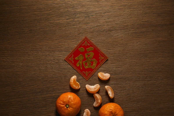 Top view of fresh ripe tangerines and golden hieroglyph on wooden table — Stock Photo