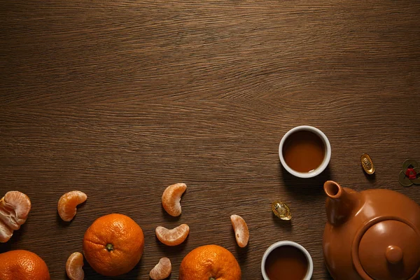 Top view of tea set, tangerines and coins on wooden surface — Stock Photo