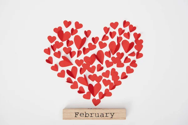 Vista superior de los corazones cortados papel decorativo y bloque de madera con letras de febrero - foto de stock