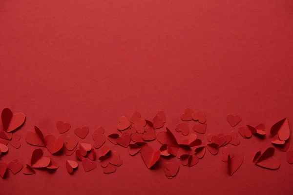 Pilha de corações de corte de papel decorativo no fundo vermelho com espaço de cópia — Fotografia de Stock