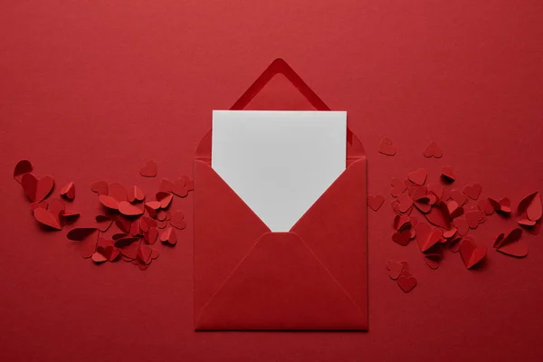 Top view of blank white letter in envelope with paper cut hearts on red background — Stock Photo