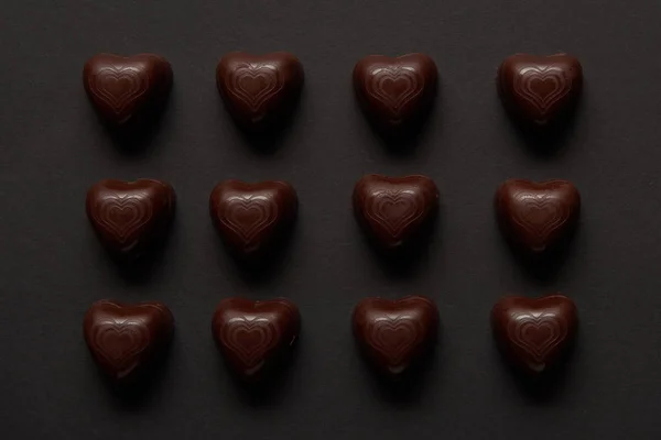 Vista dall'alto di dolci cuori di cioccolato su sfondo nero — Foto stock