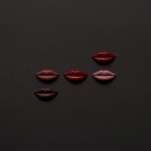 Vue du haut des lèvres en chocolat multicolore sucré sur fond noir — Photo de stock