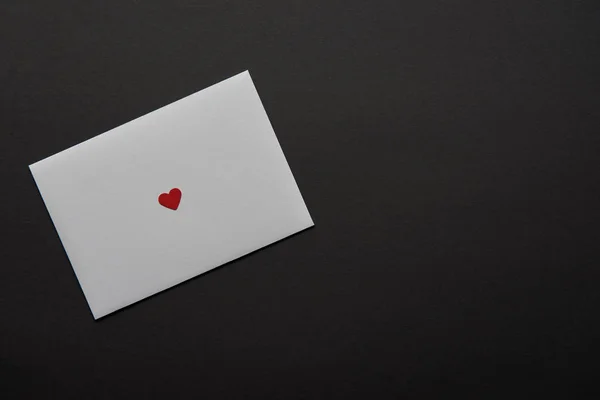 Top view of white greeting card with red heart sign isolated on black — Stock Photo