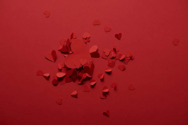 Vista superior del papel decorativo corazones cortados sobre fondo rojo - foto de stock