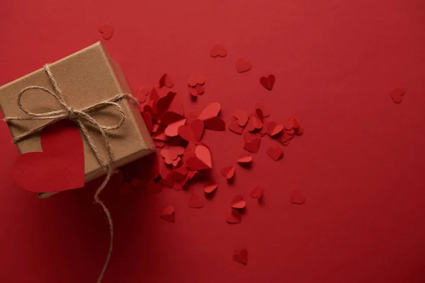 Top view of decorative paper cut hearts and gift box with empty card on red background — Stock Photo