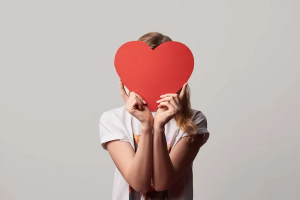 Girl with obscure face and empty paper cut heart card isolated on grey — Stock Photo