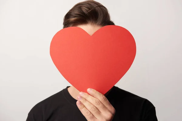 Man with obscure face holding empty paper cut heart card isolated on grey — Stock Photo